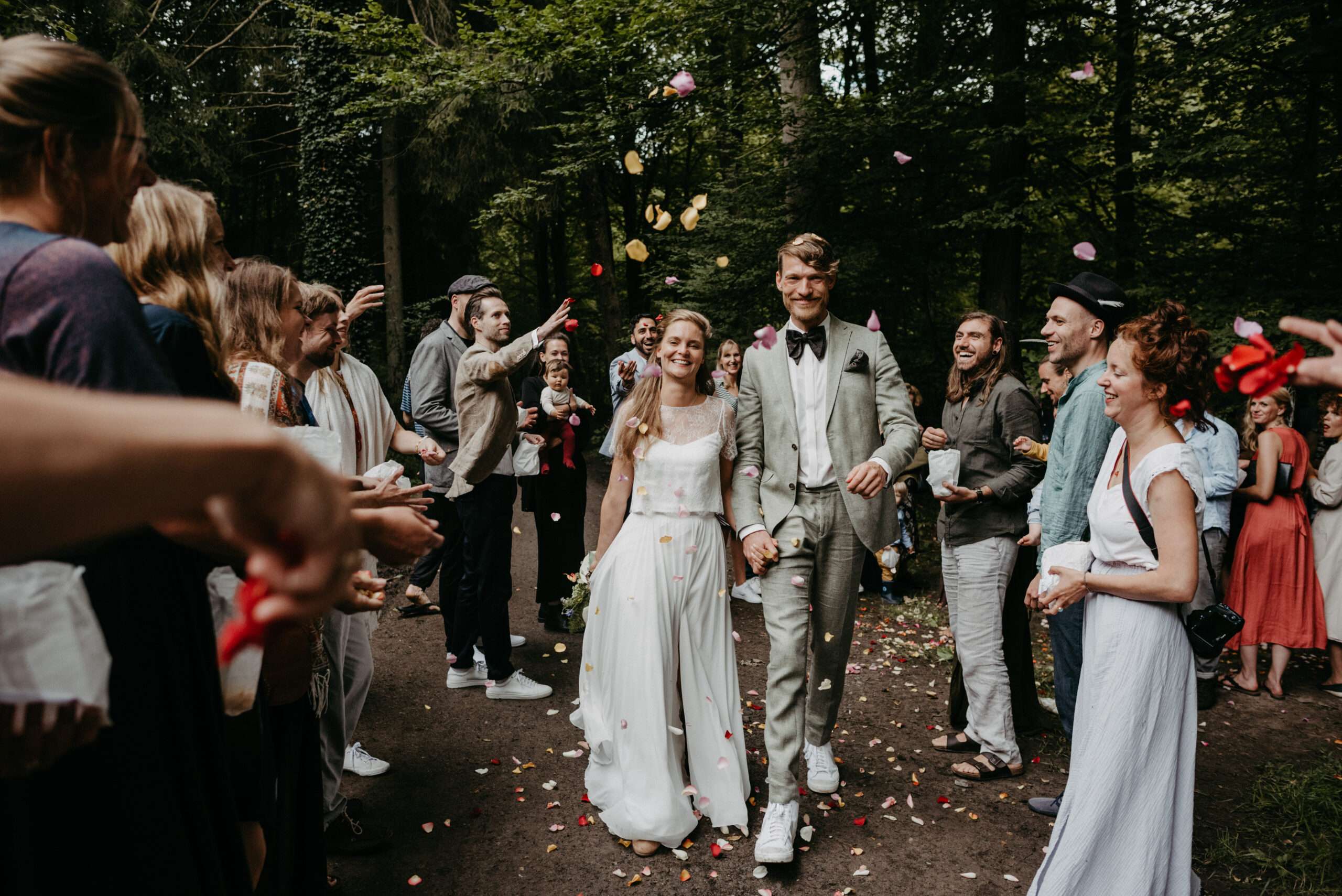 Brautpaar wird nach einer Hippie Trauumg im Wald mit Blüten beworfen, fotografiert von Daria Lanzet