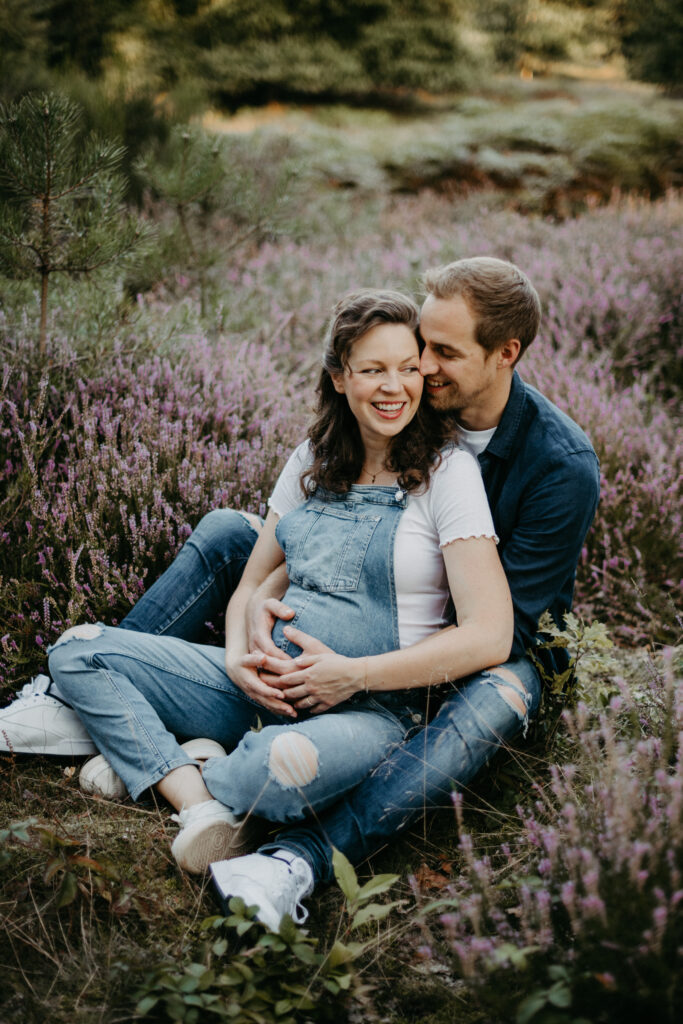Paar sitzt beim Babybauchfotoshooting auf dem Boden