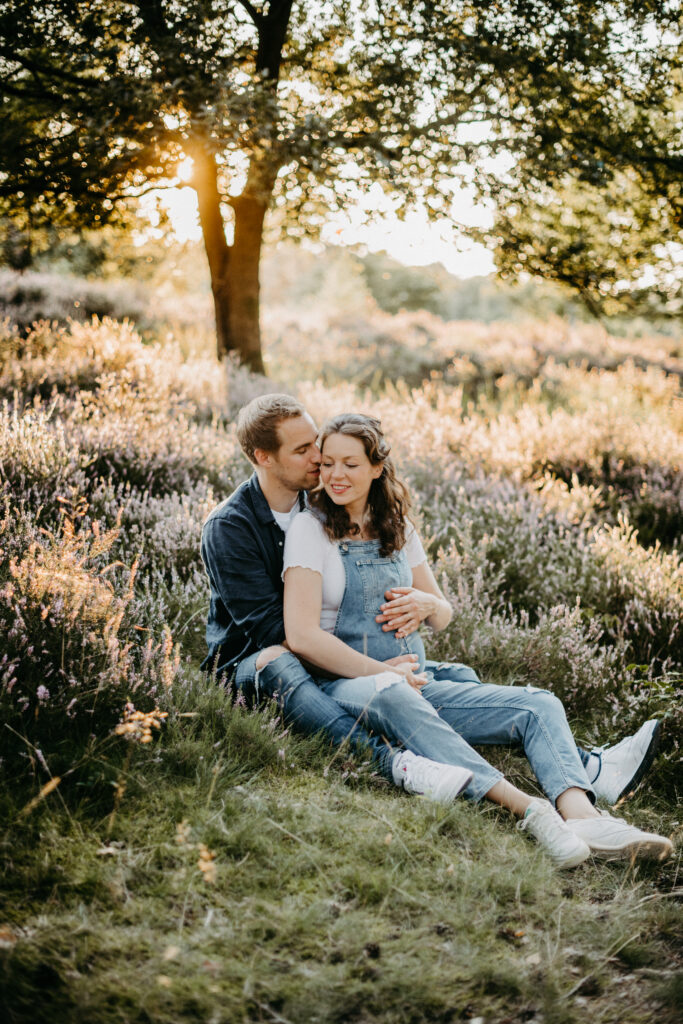 Paar sitzt beim Babybauchfotoshooting auf dem Boden