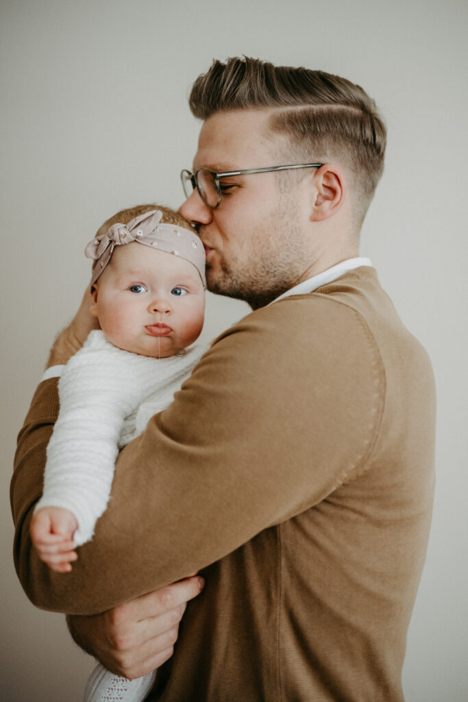 Vater küsst sein Baby vor  beim Weihnachtsmarkt-Fotoshooting für Familien in Bonn