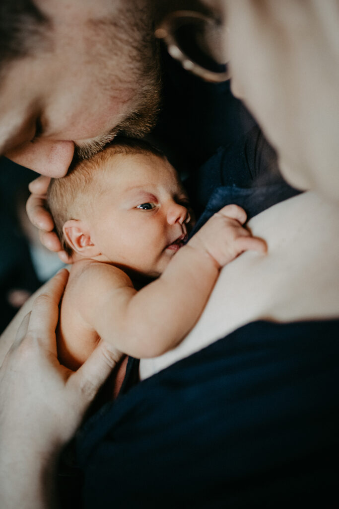 Der Vater gibt seinem neugeborenen Baby einen Kuss auf den Kopf