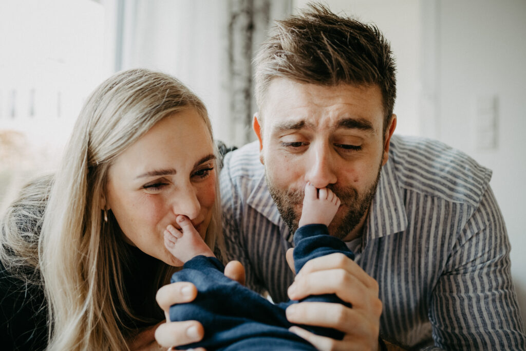 Eltern machen Spaß und kitzeln und küssen die Füße ihres Babys beim Baby-Fotoshooting in Rheinbach